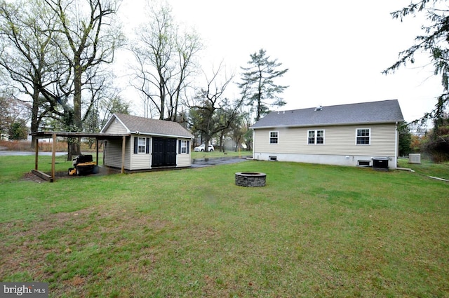 view of yard with an outdoor fire pit, an attached carport, an outdoor structure, and central AC