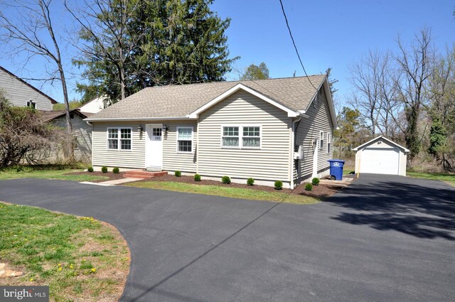 view of front of home with a shingled roof, entry steps, a detached garage, aphalt driveway, and an outdoor structure