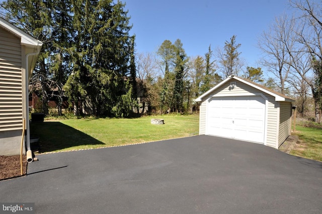 view of yard featuring aphalt driveway, an outdoor structure, and a detached garage