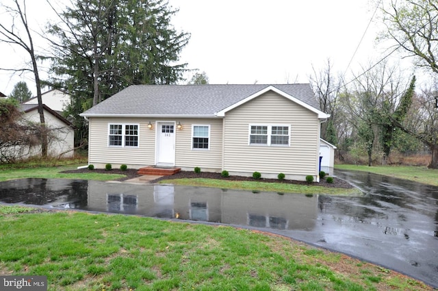 ranch-style home with a shingled roof and a front lawn