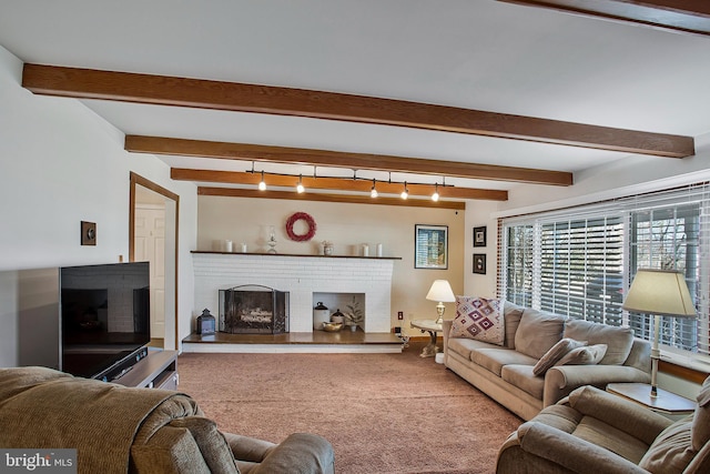 carpeted living area featuring beamed ceiling, rail lighting, and a brick fireplace
