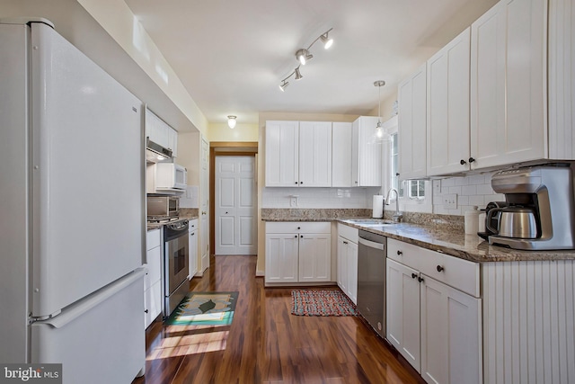 kitchen with dark wood-style flooring, white cabinets, decorative backsplash, stainless steel appliances, and a sink