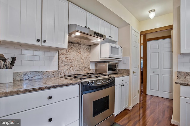 kitchen with under cabinet range hood, white microwave, stainless steel range with gas stovetop, and white cabinetry