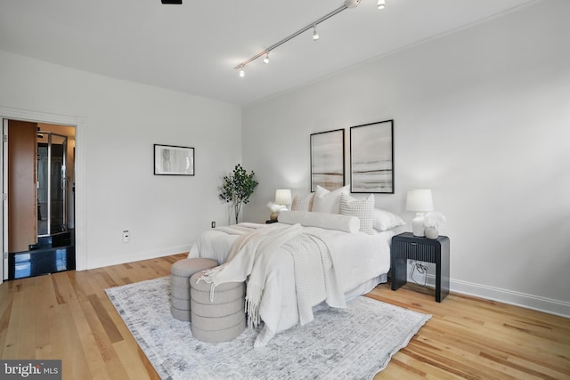 bedroom with light wood-style flooring, rail lighting, and baseboards