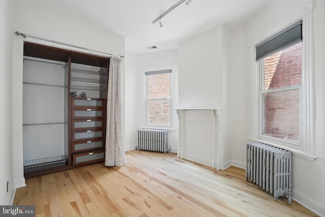 unfurnished bedroom featuring radiator, wood finished floors, and multiple windows