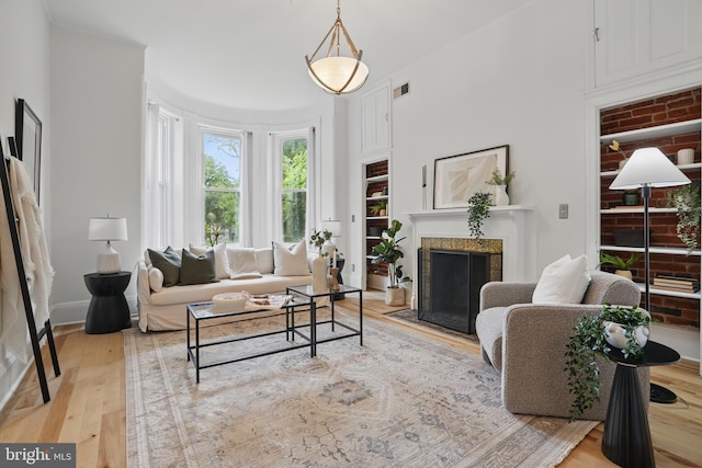 living room featuring light wood finished floors, a fireplace with flush hearth, and baseboards