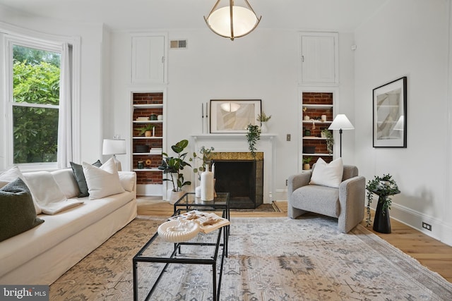 living area featuring wood finished floors, baseboards, and a fireplace with flush hearth