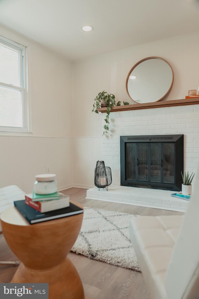 living room with a brick fireplace, wood finished floors, and recessed lighting