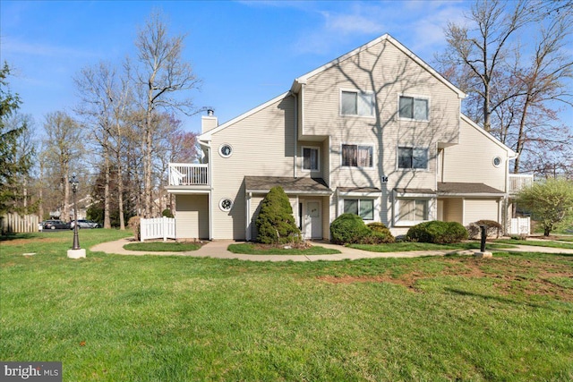 view of front of property featuring a chimney, a front lawn, and a balcony