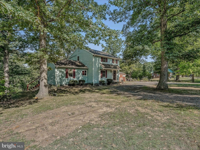 view of front of property featuring dirt driveway and a front lawn
