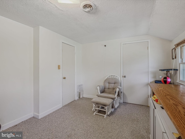 living area with a textured ceiling, lofted ceiling, baseboards, light colored carpet, and visible vents
