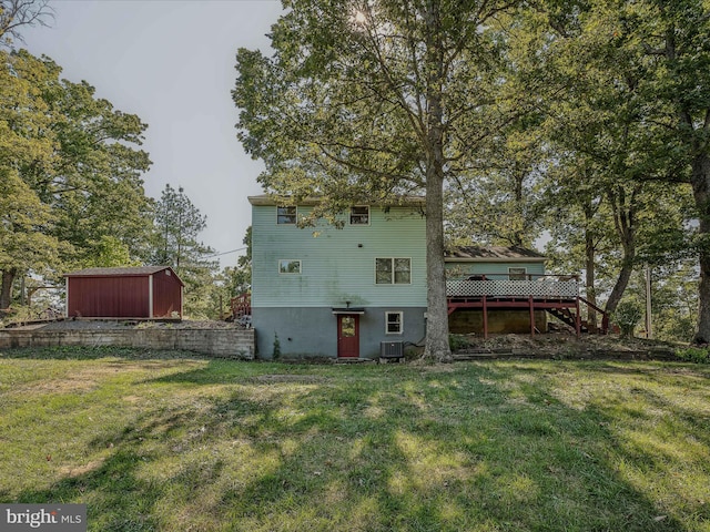 rear view of property featuring an outbuilding, a deck, and a yard