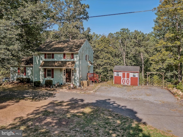 view of front of house featuring driveway, an outdoor structure, and a storage shed