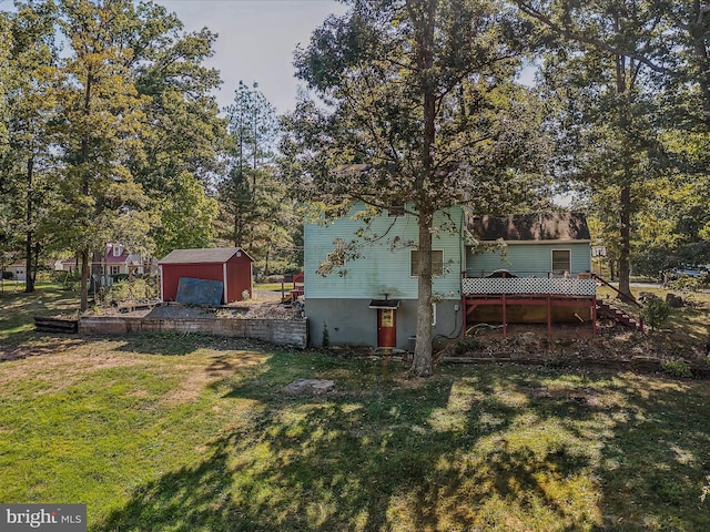 rear view of property with a storage unit, an outbuilding, a deck, and a yard