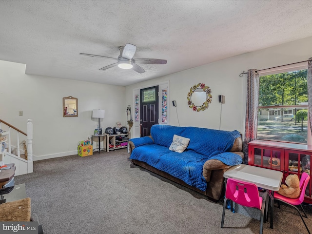 living area featuring baseboards, carpet floors, a textured ceiling, and a ceiling fan