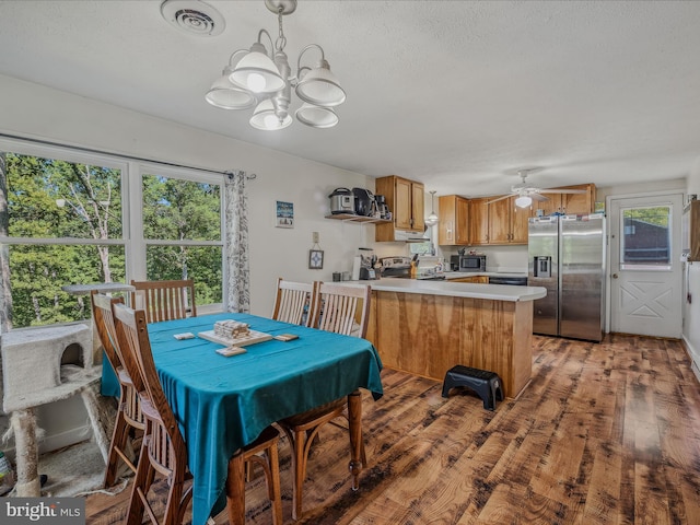 dining space featuring light wood-type flooring, ceiling fan with notable chandelier, a healthy amount of sunlight, and visible vents