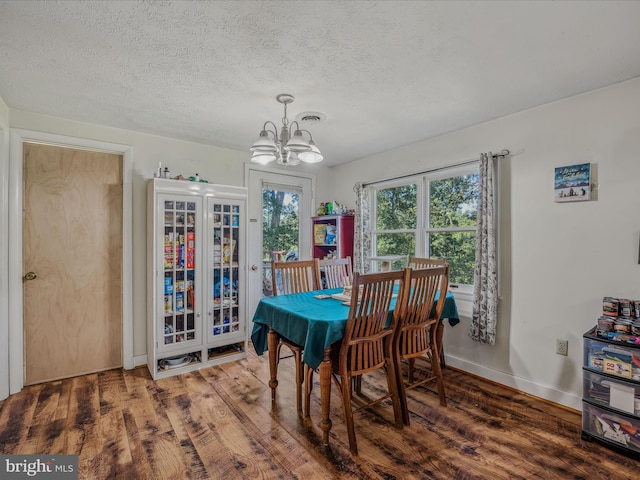 dining space with a textured ceiling, baseboards, a chandelier, and wood finished floors