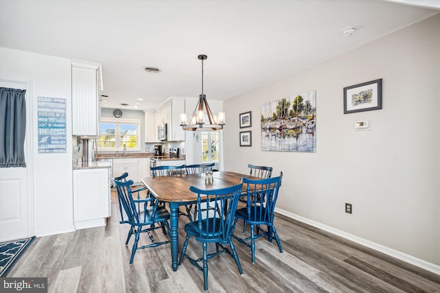 dining space featuring baseboards, visible vents, light wood-style flooring, and an inviting chandelier