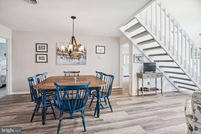 dining room featuring baseboards, stairs, wood finished floors, and an inviting chandelier