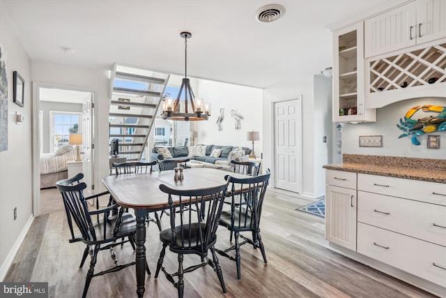 dining room with baseboards, visible vents, an inviting chandelier, and light wood finished floors