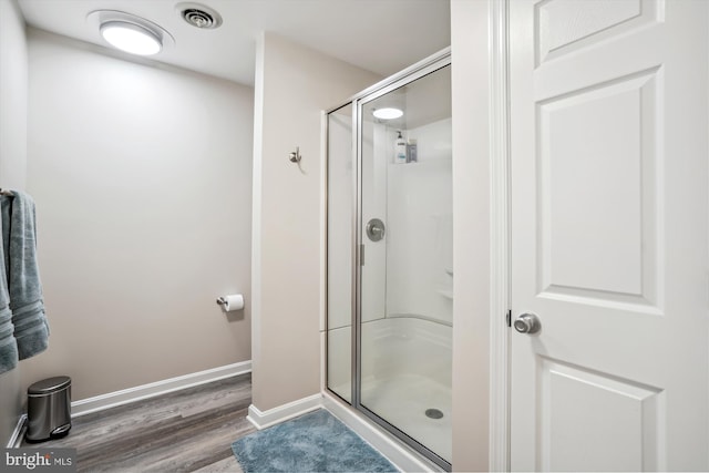 full bathroom featuring wood finished floors, a stall shower, baseboards, and visible vents