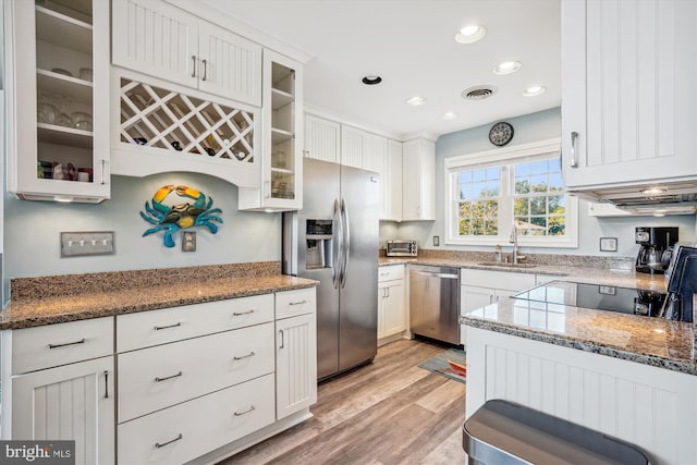 kitchen with a sink, white cabinetry, light wood-style flooring, stainless steel appliances, and visible vents