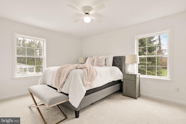 bedroom with multiple windows, light colored carpet, and baseboards