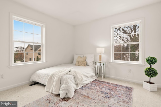 bedroom featuring baseboards, multiple windows, and carpet