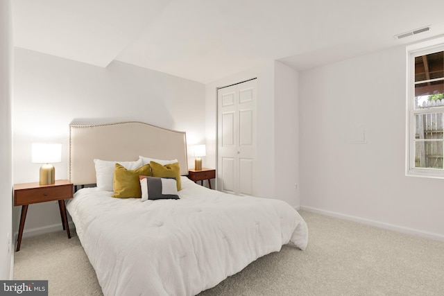 bedroom featuring a closet, light carpet, baseboards, and visible vents