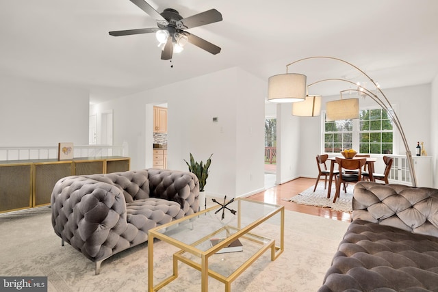 living room with baseboards, light wood finished floors, and ceiling fan