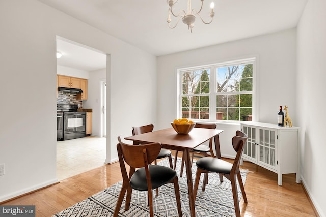 dining room with light wood-style flooring, baseboards, and a chandelier