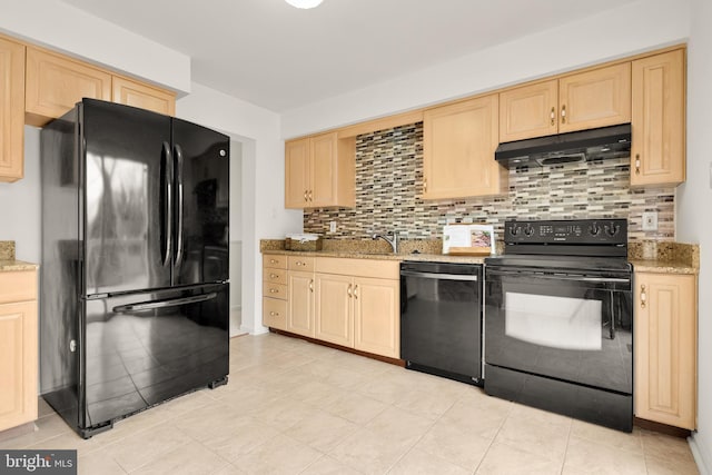 kitchen with light brown cabinetry, under cabinet range hood, backsplash, light stone countertops, and black appliances