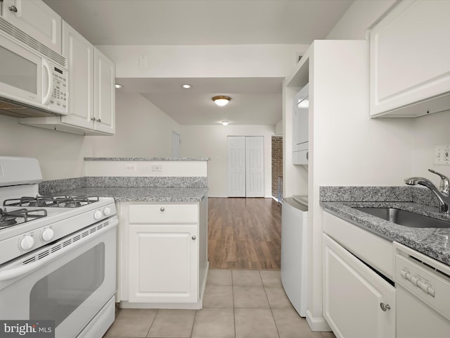 kitchen with white appliances, white cabinets, and a sink