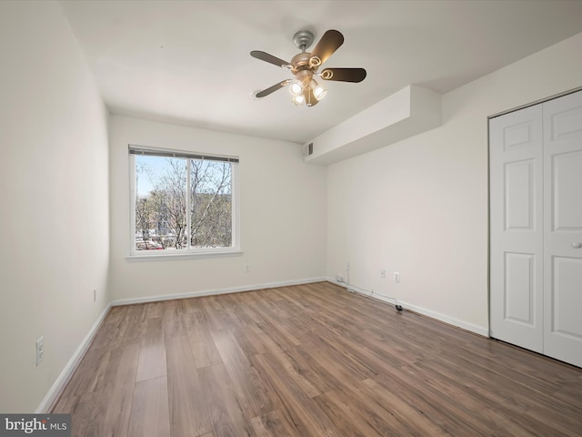 unfurnished bedroom featuring a closet, wood finished floors, baseboards, visible vents, and ceiling fan