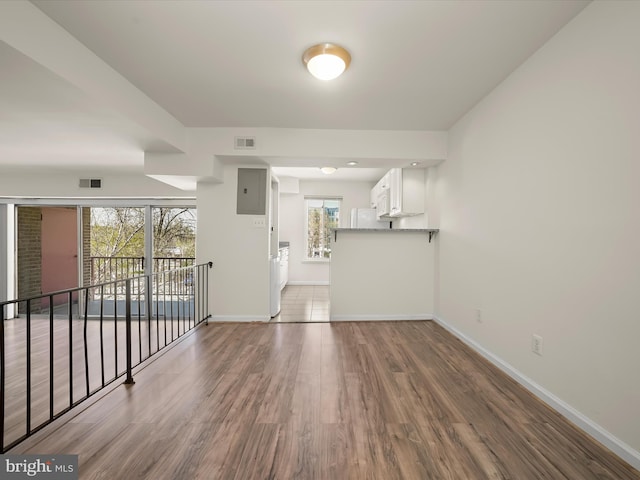 unfurnished living room with baseboards, visible vents, and wood finished floors