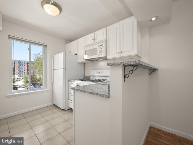 kitchen featuring baseboards, white cabinetry, light stone counters, and white appliances