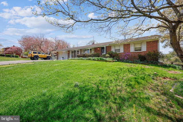 single story home featuring concrete driveway, a garage, brick siding, and a front yard