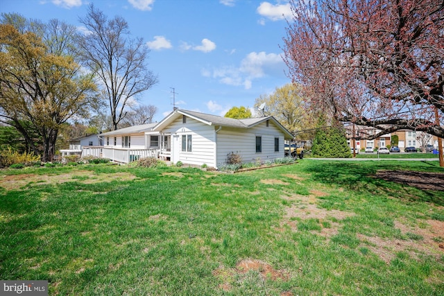 view of side of home featuring a wooden deck and a lawn