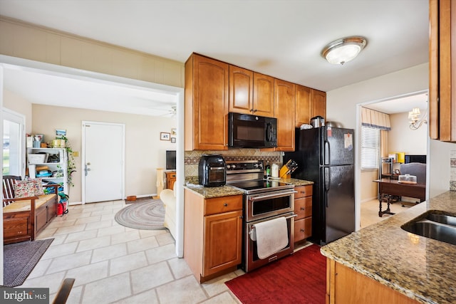 kitchen featuring light stone countertops, tasteful backsplash, black appliances, and brown cabinets