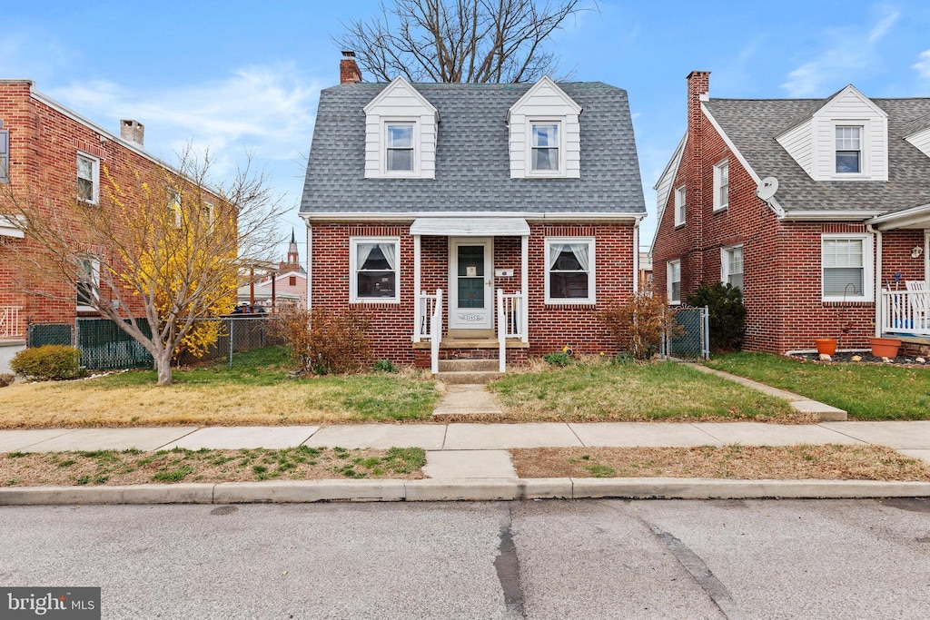 view of front of property featuring a chimney, fence, a front lawn, and brick siding