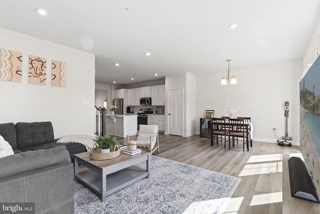 living room featuring light wood-style floors, recessed lighting, baseboards, and an inviting chandelier