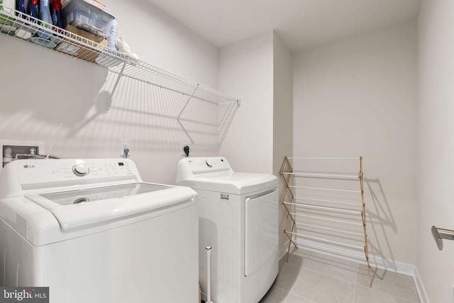 laundry area featuring baseboards, separate washer and dryer, laundry area, and light tile patterned flooring