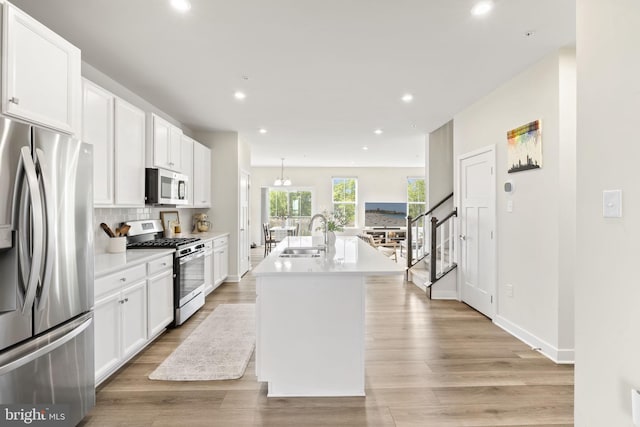 kitchen featuring decorative backsplash, light countertops, white cabinets, a sink, and appliances with stainless steel finishes