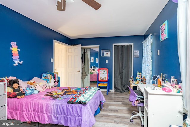 bedroom featuring multiple closets, ceiling fan, and wood finished floors