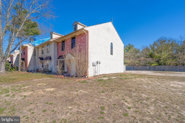 view of home's exterior with a yard, stucco siding, and fence