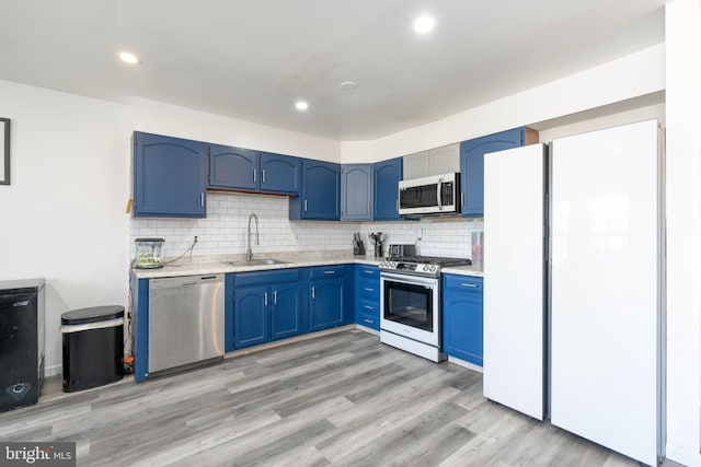 kitchen featuring light countertops, light wood finished floors, stainless steel appliances, a sink, and blue cabinets