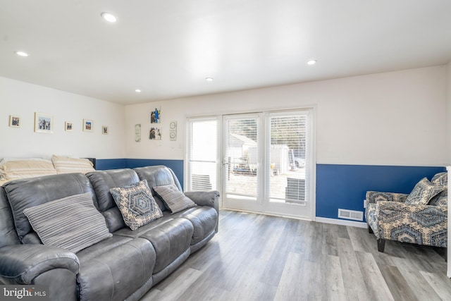 living area featuring baseboards, visible vents, wood finished floors, and recessed lighting