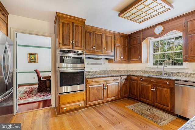 4300 Valleyview Rd, Harrisburg, PA 17112 - kitchen with appliances with stainless steel finishes, a sink, under cabinet range hood, light wood-type flooring, and light stone countertops