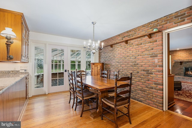 4300 Valleyview Rd, Harrisburg, PA 17112 - dining room with brick wall, light wood-style floors, a chandelier, and a brick fireplace
