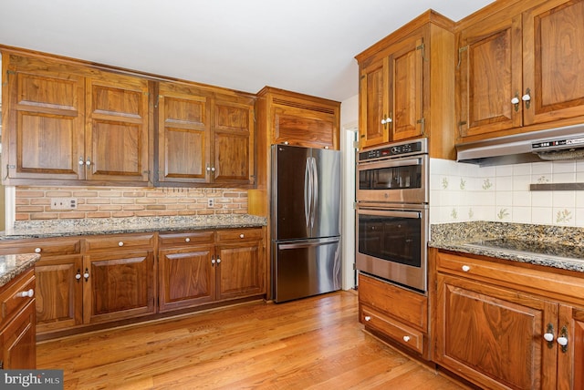 4300 Valleyview Rd, Harrisburg, PA 17112 - kitchen with appliances with stainless steel finishes, under cabinet range hood, brown cabinetry, and tasteful backsplash